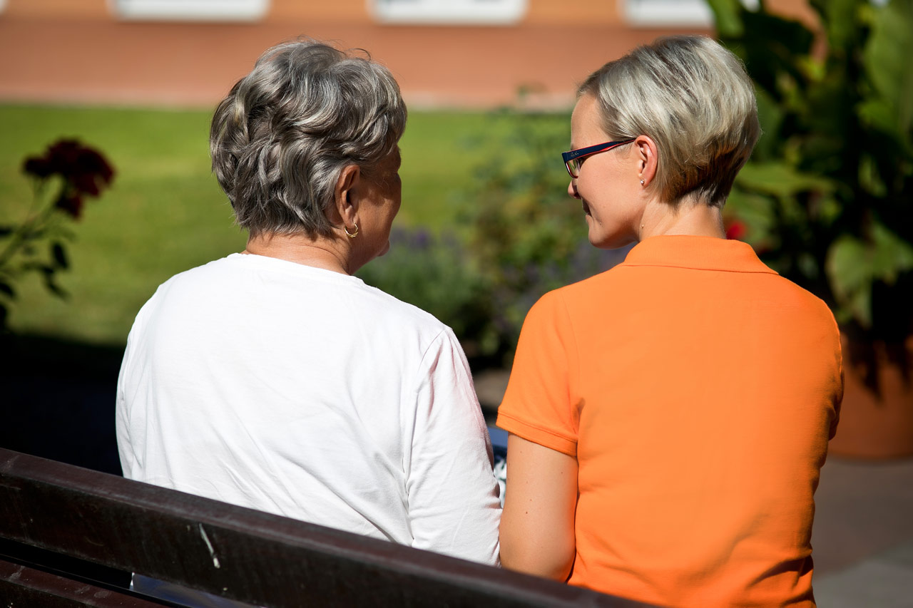 Frau im Ehrenamt mit Senioren sitzen auf einer Bank